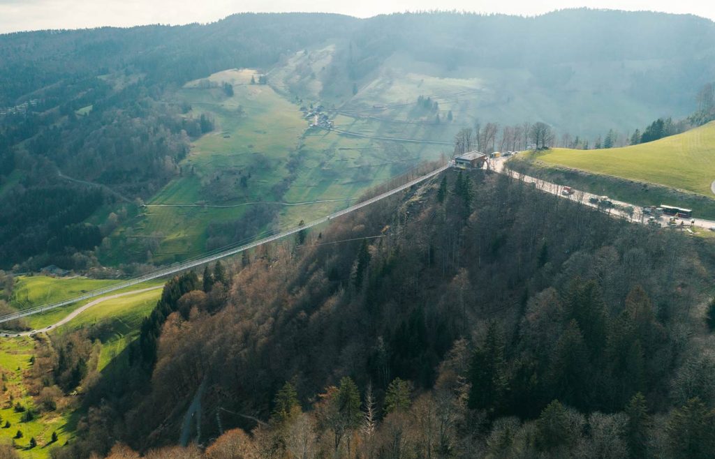 Die Brücke von der Seite: ein dünner Steg über der Schlucht, am rechten Ende das Besucherhaus mit Parkplatz