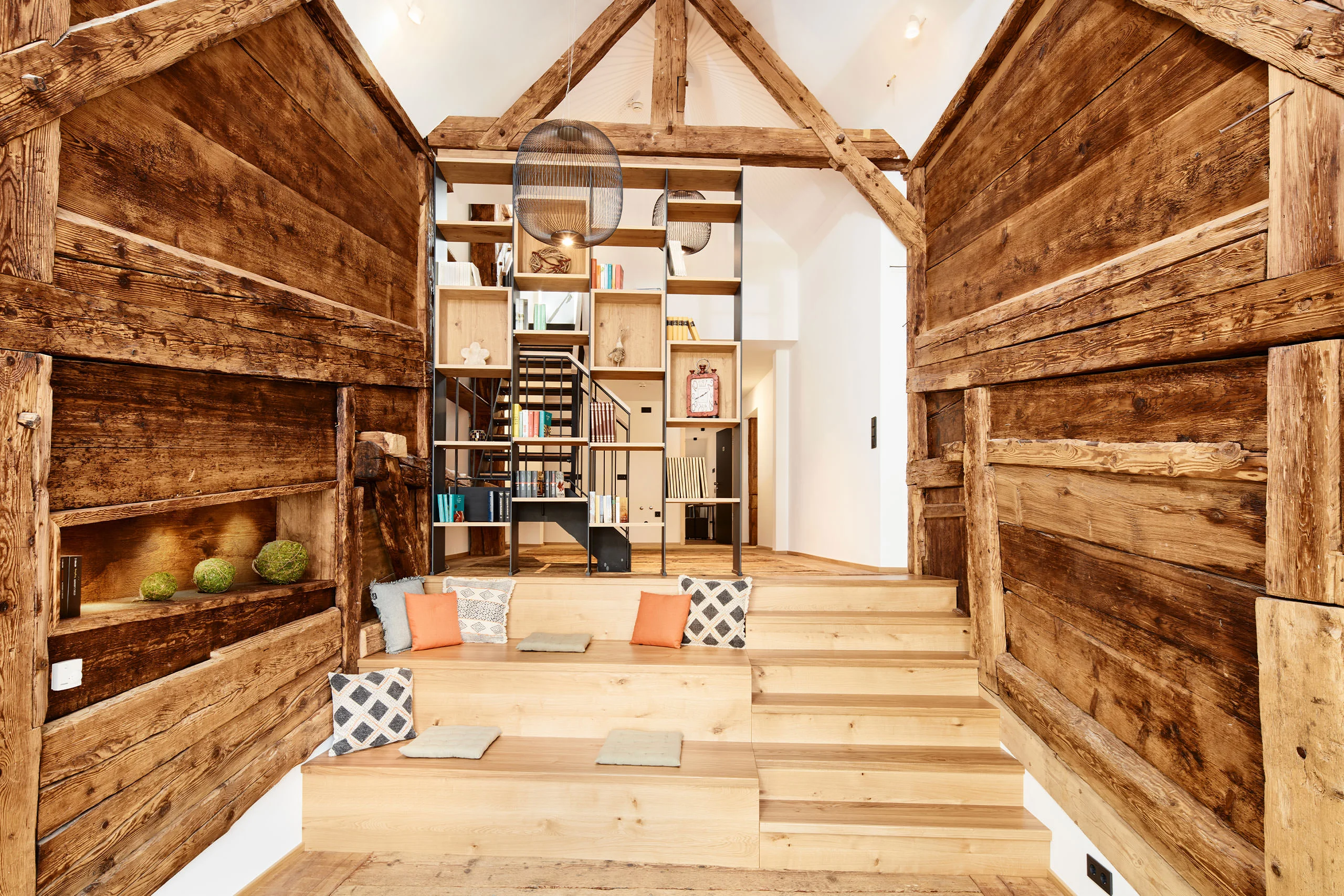 Bibliothek mit Sitzstufen und Regal zwischen Holzwänden im Bruderhof in Menzenschwand