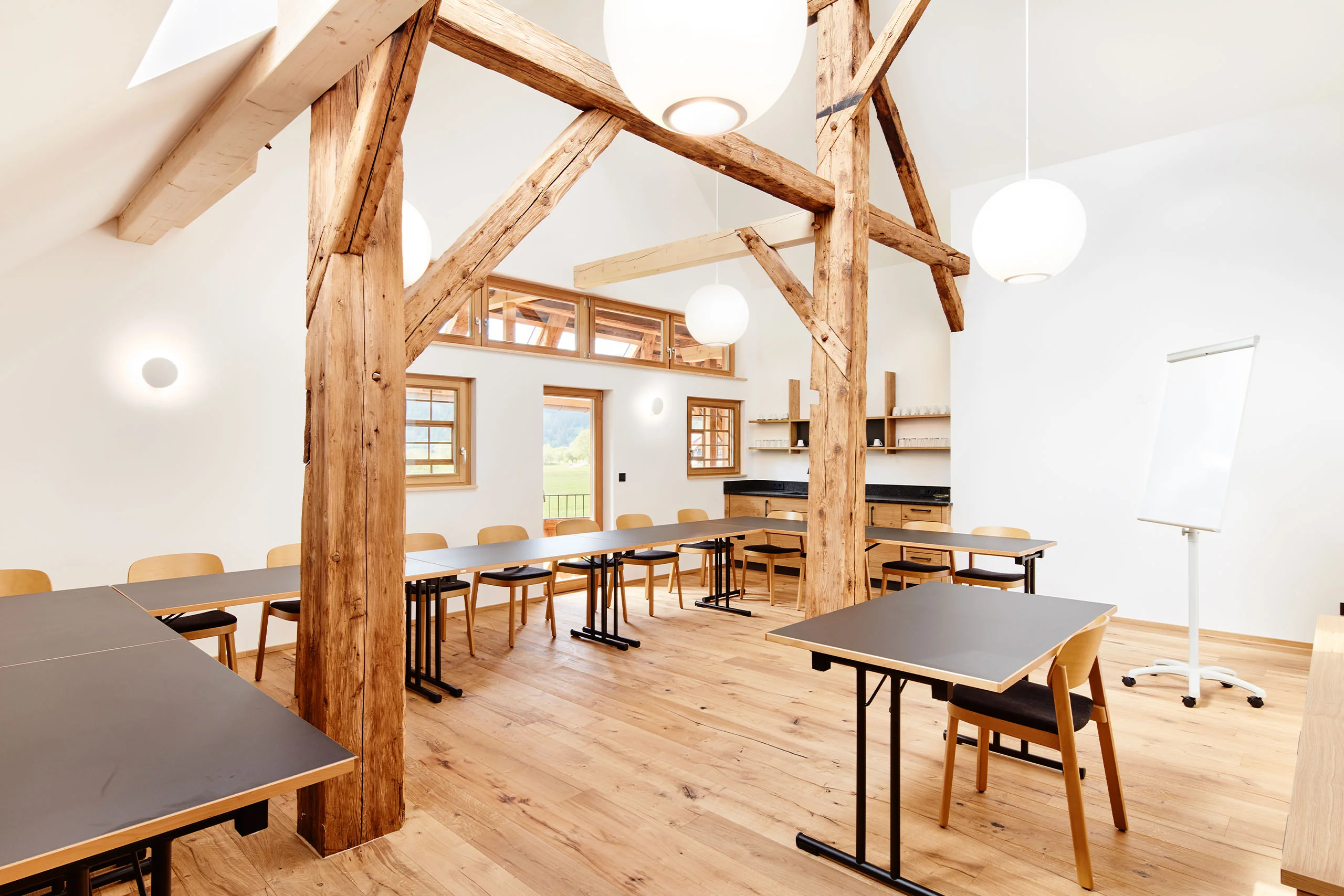 Konferenzraum unter dem Dachgebälk mit Tischreihen im Bruderhof in Menzenschwand