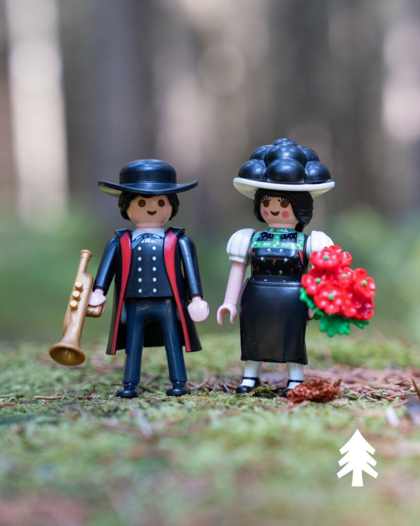 Nahaufnahme aus dem Playmobil-Set 71927: Schwarzwald Marie mit schwarzem Bollenhut und rotem Blumenstrauß, Hannes mit goldener Trompete